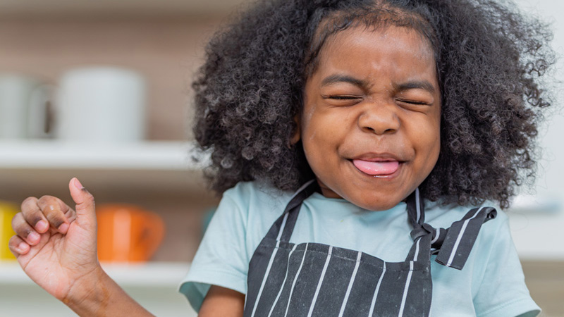 A young girl makes a grimacing face after tasting something bitter