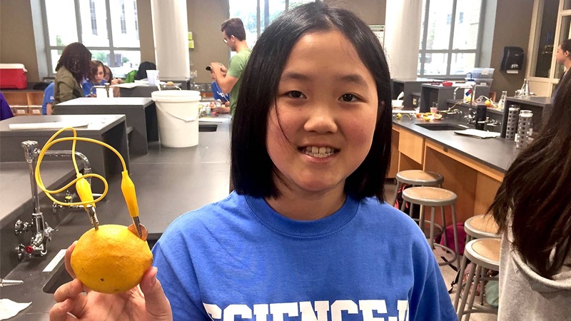 A young girls showing off a lemon wired as a battery.