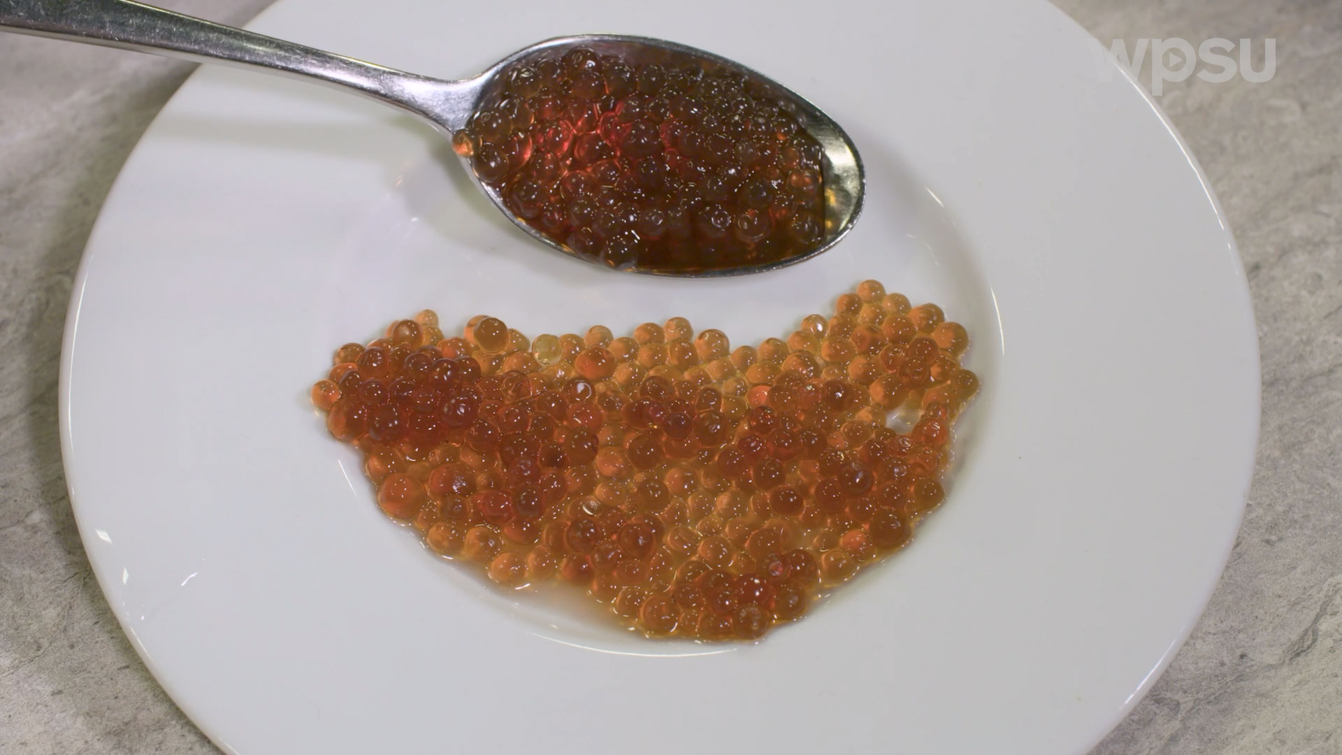 Small edible balls filling a plate and spoonl