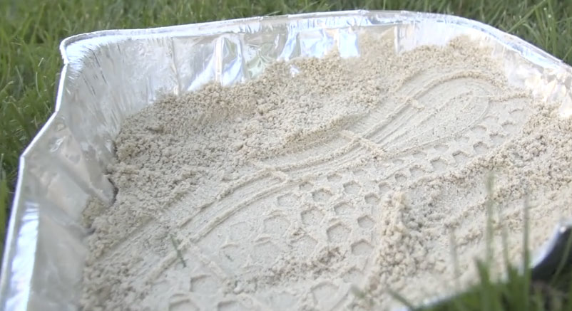 Casting of a shoe print in a pan of kinetic sand.